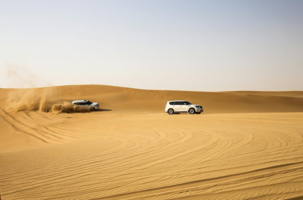 Two SUVs driving through the dunes in Abu Dhabi desert, capturing thrilling adventure moments.
